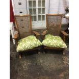 A pair of cottage armchairs having tapering caned backs above loose cushion seats, the shaped