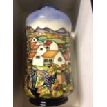 A boxed Moorcroft tubular waisted tube-lined vase with continuous mountain village scene above vines