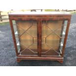 A mahogany china cabinet with moulded top above astragal glazed doors enclosing glass shelves with