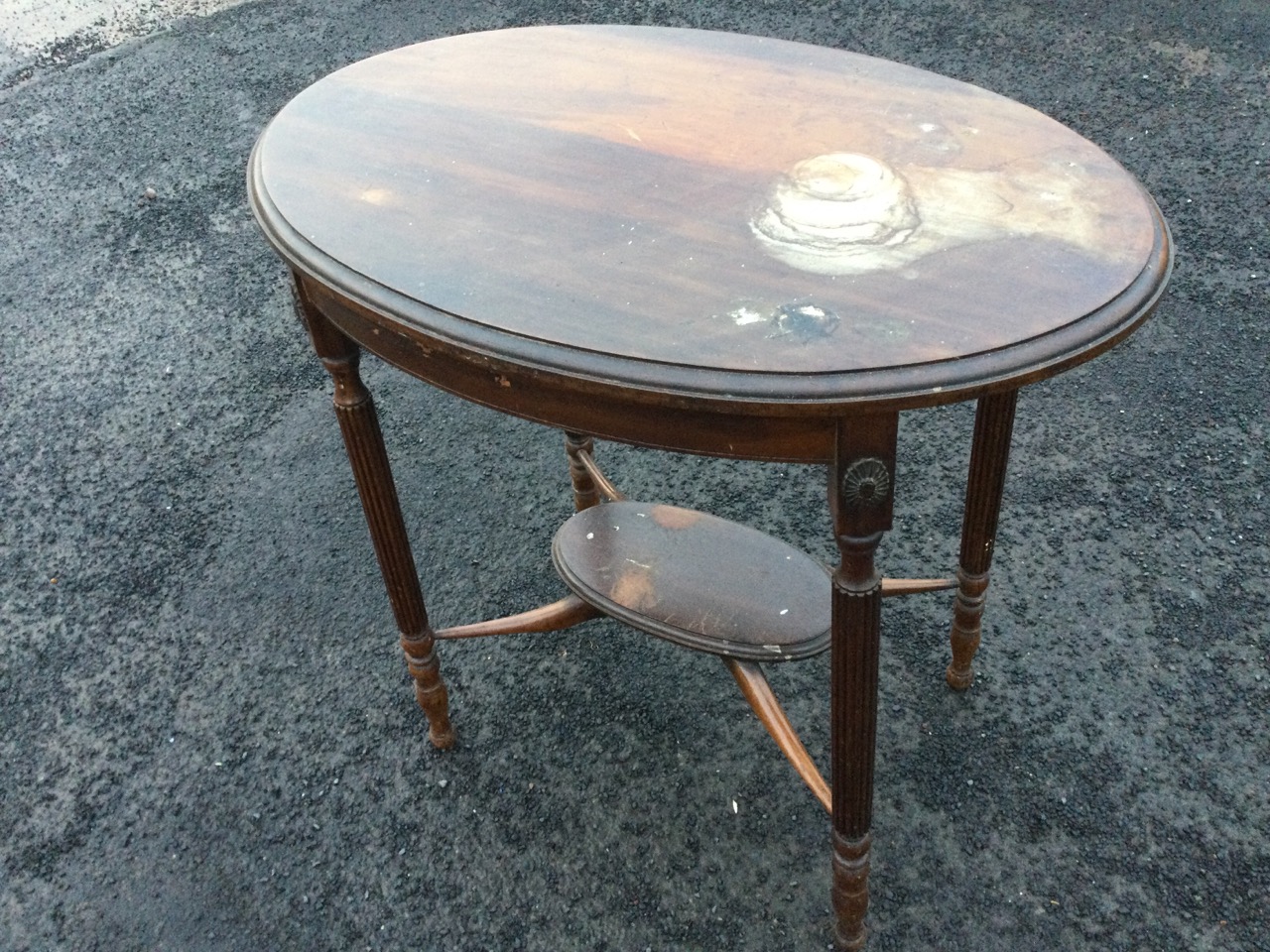 An oval mahogany occasional table, the moulded top on reeded column legs with applied floral