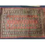 An oriental rug woven in the tekke style with red field of twenty-two oval lozenges framed by