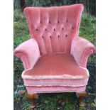 An upholstered armchair with tapering buttoned back above a loose cushion and sprung seat, raised on