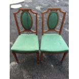 A pair of Edwardian mahogany satinwood banded chairs with oval upholstered panels to backs above