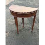 An Edwardian mahogany turn-over-top card table of D shaped outline with lozenge carved edge and