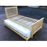 A single oak bed with slatted headboard & tailboard on rectangular legs, having a further bed &