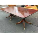 A Georgian style twin pedestal mahogany dining table, the top with spare leaf having ribbed edge,