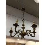 A hanging brass chandelier with five acanthus cast scrolled branches on bun beneath a column,