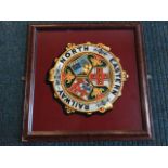 A circular North East Railway coloured printed medallion with three armorial shields in titled