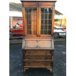 A 1930s oak bureau bookcase with moulded cornice above a frieze with applied decoration and leaded