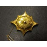 An 18ct gold brooch with fine applied beadwork to oval on scalloped panel, centered by a bead, the