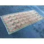 An oriental rug woven with floral designs on pink field framed by brown border, with leaf and