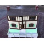 A large C20th dolls house with pitched roof above a timbered building, the front elevation opening
