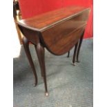 An oval Edwardian mahogany supper table, the moulded top with drop-leaves raised on slender tapering