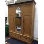 A Victorian bleached mahogany wardrobe with moulded cornice above an oval bevelled mirror panel