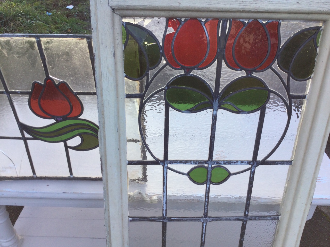 A set of three leaded stained glass windows with central red tulip design; and another similar in