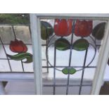 A set of three leaded stained glass windows with central red tulip design; and another similar in