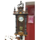 A Victorian walnut cased Vienna wallclock, the pediment with horse above a panel with masque and