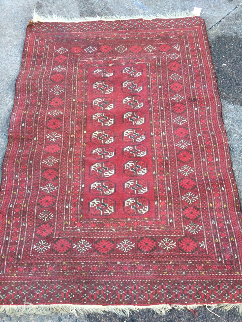 An Afghan rug woven with field of eighteen octagonal lozenges within multiple floral borders, the