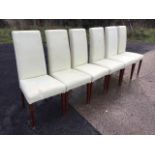 A set of six cream leather upholstered dining chairs, with tall backs above tapering seats, raised