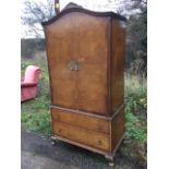 A Queen Anne style walnut press with arched crossbanded cupboard having foliate carved pierced crest