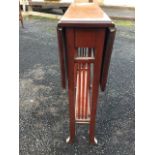 An Edwardian mahogany sutherland table with serpentine shaped drop leaves on ends with spindles,