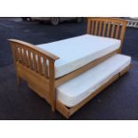 An oak single bed with arched headboard & tailboard above slats raised on rectangular legs, having a