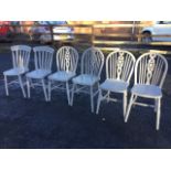 A set of four grey painted wheelback kitchen chairs, with solid seats and arched backs on