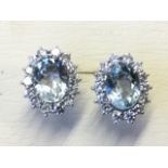 A pair of 18ct white gold aquamarine & diamond earrings, the oval claw set aquamarine stones of just