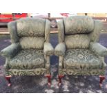 A pair of Queen Anne style upholstered wing armchairs, with padded backs and loose cushions above