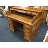 An oak roll-top desk, the fitted interior enclosed by a tambour above a kneehole with arched