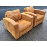 A pair of suede leather deco style armchairs, the backs with loose cushions above arched arms,