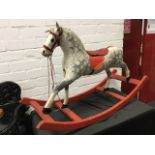 A C20th century carved wood rocking horse, the animal with later painted decoration and tack, raised