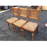 A set of three Danish carved oak dining chairs, the backs with pieced scroll carved panels flanked