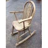 An oak wheelback rocking chair, the arched back on spindles and pierced splat, above a solid
