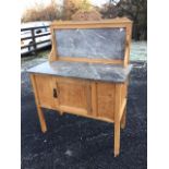 An Edwardian stripped marble topped mahogany washstand, the back with scrolled carving above a panel