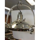 An industrial style chrome ceiling light, the gimbal style cup mount supporting a curved bracket