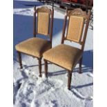 A pair of late Victorian carved oak chairs, the arched backs with leaf panels above upholstered