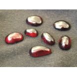 Seven loose polished garnets, the shaped cabouchon unfaceted stones of various sizes from half an