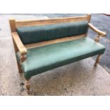 An upholstered settle, the padded back in moulded frame with shaped arms on turned columns, the seat