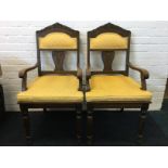 A pair of carved oak armchairs, the arched backs with leaf and scrolled rails above rectangular