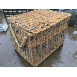 A large cane basket with hinged lid, raised on wood battons with wheels. (39.5in x 31in x 28.5in)