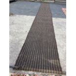 A long coconut mat style grass runner, the stripped woven matting with turned ash poles. (32in x