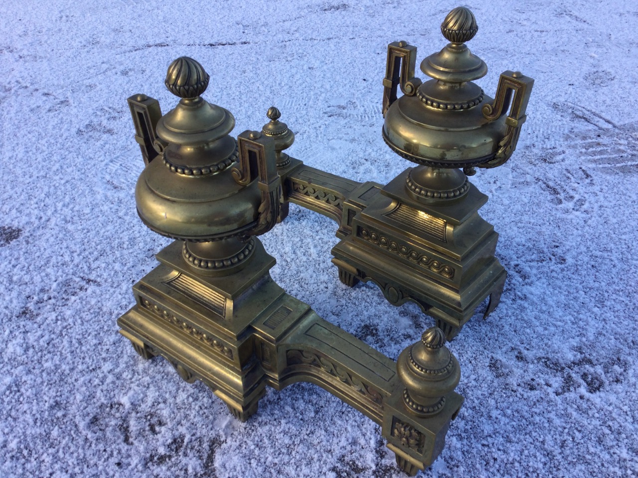 A pair of nineteenth century classical brass chenets with urns having acanthus scrolled handles on