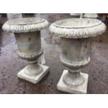 A pair of composition garden urns with lozenge moulded rims on fluted tapering bodies, with square