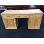 A modern oak kneehole desk, the rectangular top having central drop-down drawer flanked by
