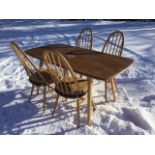 An elm Ercol dining suite, the rectangular rounded table on angled legs, the chairs with hooped