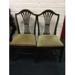 A pair of mahogany Hepplewhite style dining chairs with arched backs above pierced splats, the