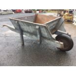 A large wood wheelbarrow, the box with angled sides and ash shafts having solid tyre and square