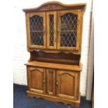 A pine dresser, the arched moulded cornice with carving above leaded glass doors mounted with