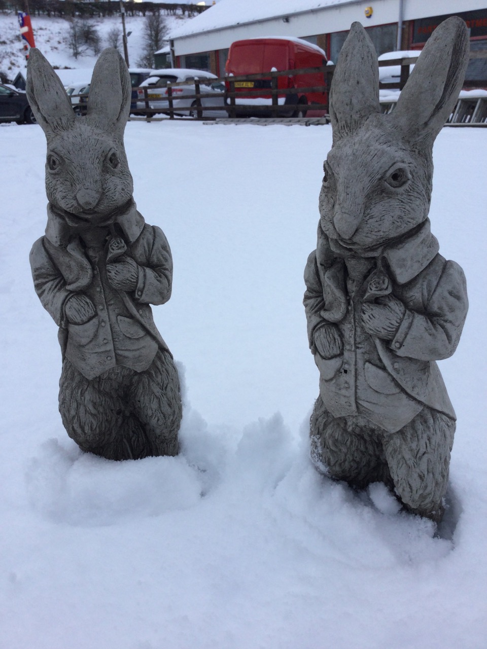 A pair of composition stone Beatrix Potter/Alice in Wonderland type rabbits, the beasts in jackets